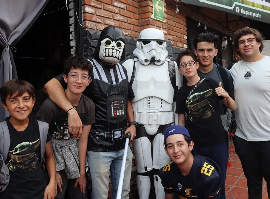 Grupo de jóvenes con un soldado imperial y Darth Vader en la entrada del café