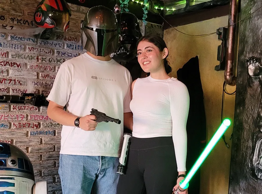 Visitante con sable verde junto a un mandaloriano y R2-D2