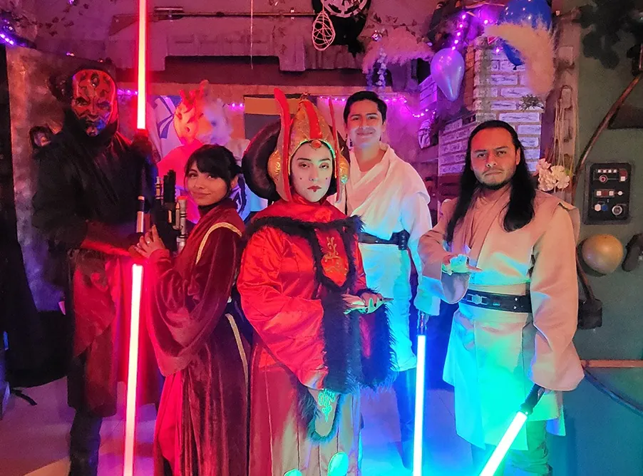 Invitados disfrazados de Sith, reina y Jedi posan con sables encendidos